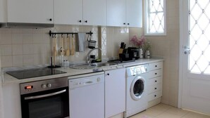 Une cuisine moderne avec des meubles blancs, un four encastré, un lave-vaisselle et un lave-linge.