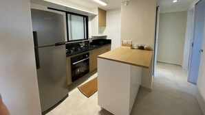 Cozinha moderna com frigorífico, fogão, forno e bancada de madeira.