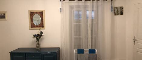 A bedroom with a bed, dresser, mirror, and a window with curtains.