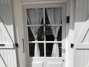 Une porte blanche avec une fenêtre, une couronne et une poignée.
