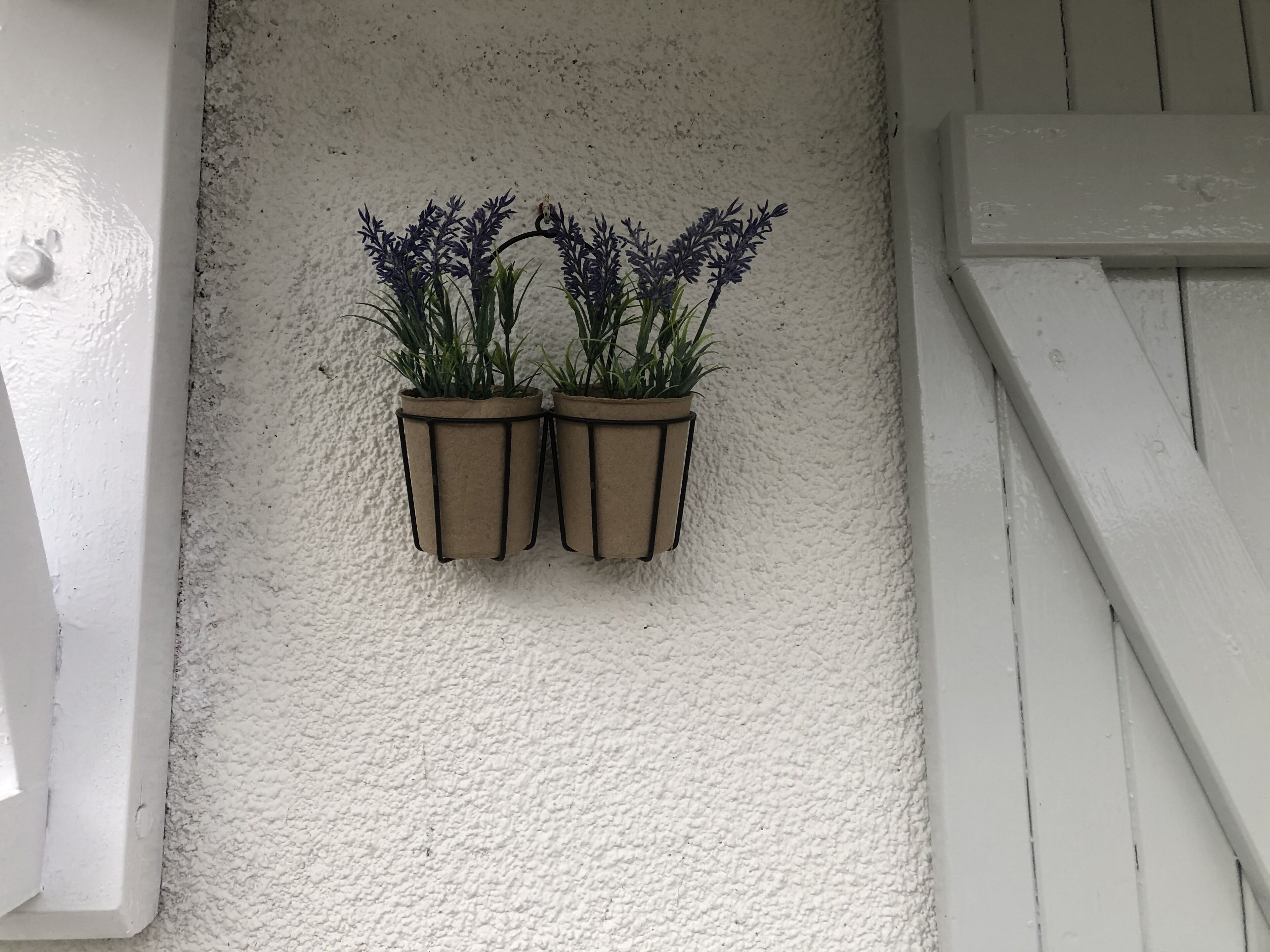 To plantekasser hænger på en væg med struktur.