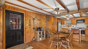 L’intérieur d’un chalet rustique comprend un coin repas, une cuisine et une porte noire.