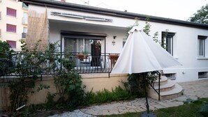 Ein weißes Gebäude mit Balkon, Blumentöpfen und einem weißen Sonnenschirm.