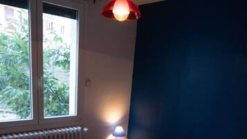 Ein Schlafzimmer mit zwei Betten, einem Fenster, einem Heizkörper und einer Hängelampe.
