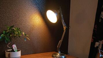 A wooden desk with a desk lamp, a potted plant, and a chair.