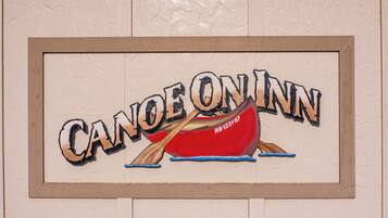 Kehyksiin asetettu kyltti, jossa lukee teksti ”CANOE ON INN” ja on kuvattuna punainen kanootti.