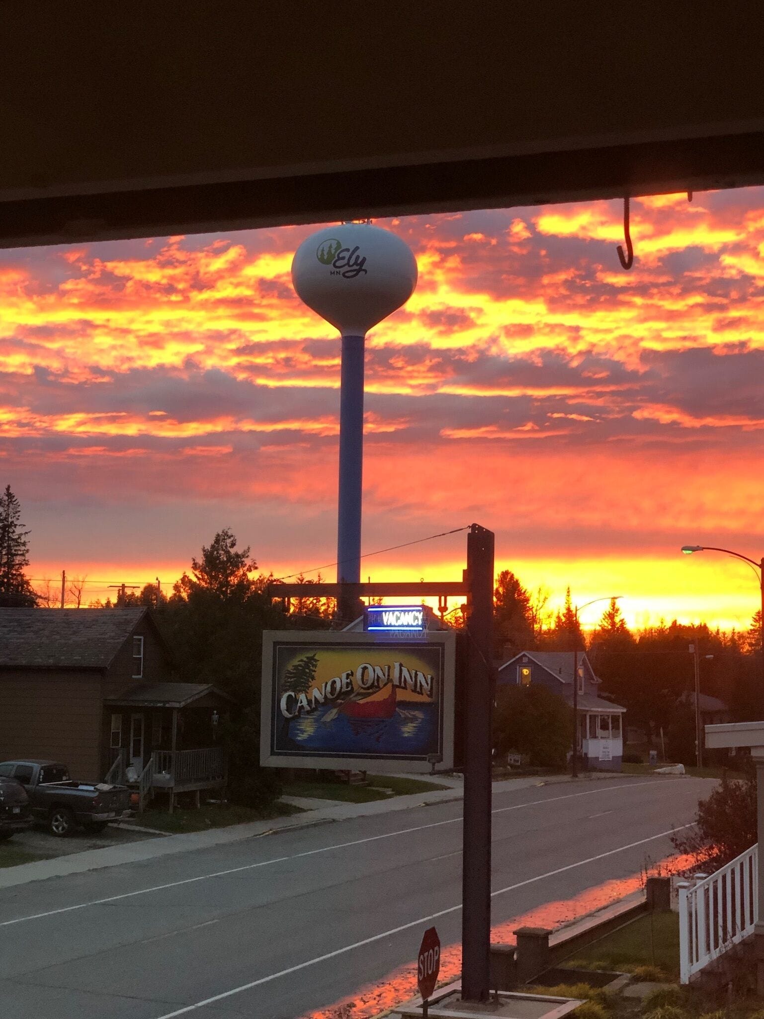 A sign for Canoe on Inn with a view of a sunset.