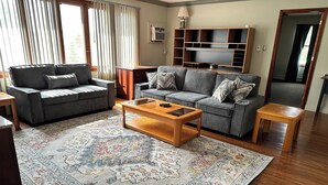 Un salon avec deux canapés gris, une table basse en bois et un tapis à motifs.