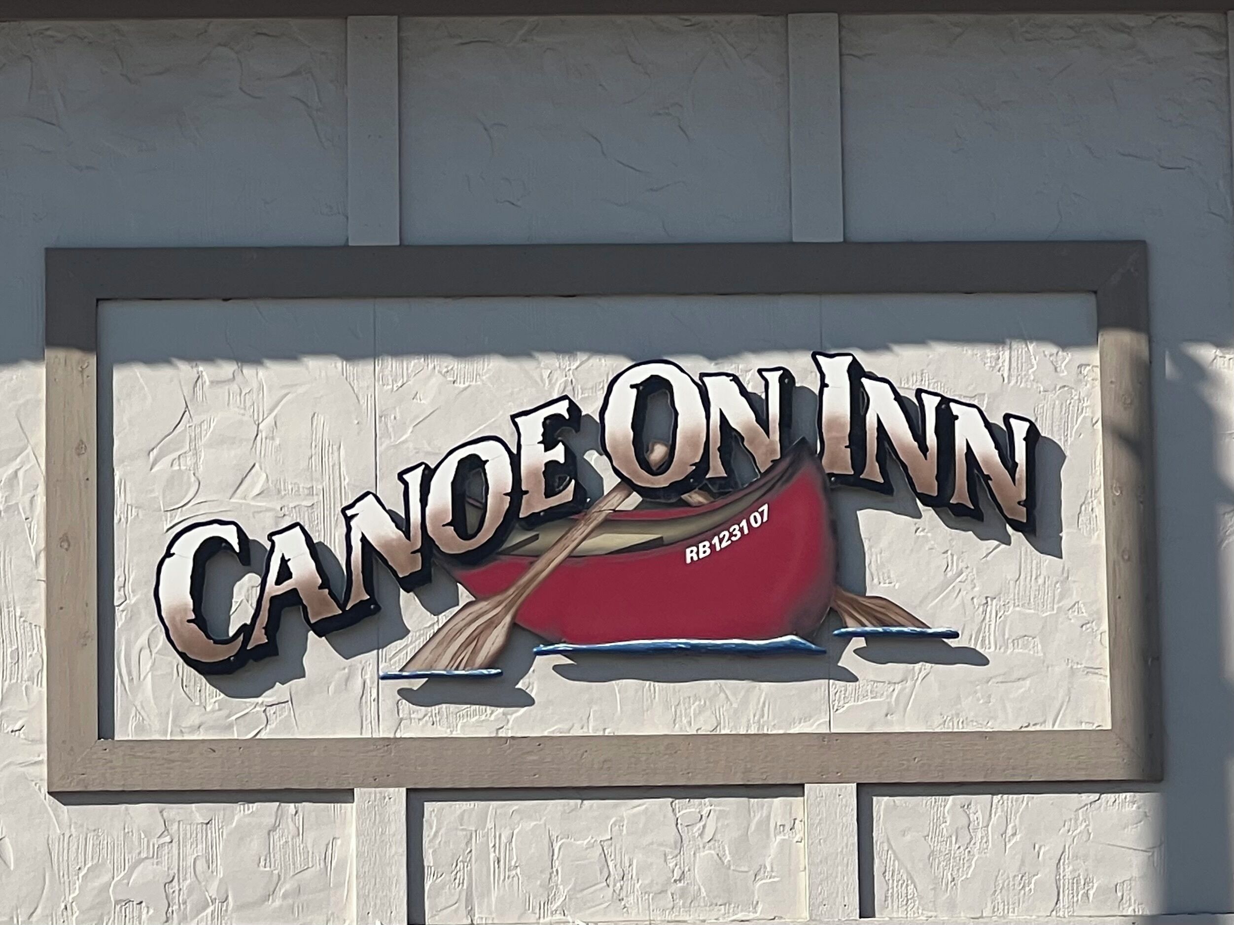 Une pancarte avec le texte « CANOEONN » et un canoë rouge avec une pagaie.