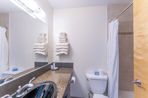 A bathroom with a sink, mirror, towel rack, toilet, and shower curtain.