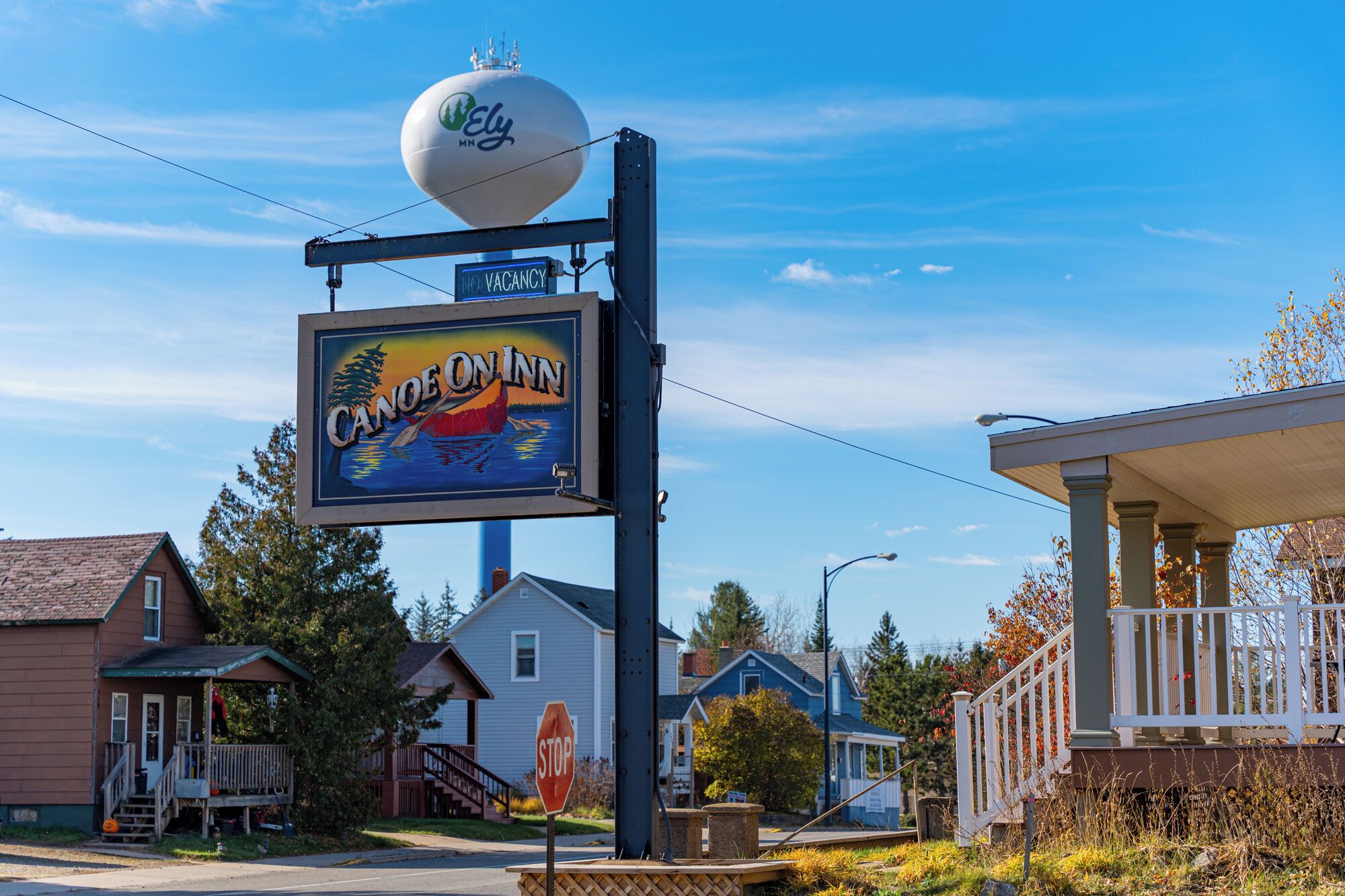 A hotel sign with a canoe and a 'No Vacancy' sign, surrounded by residential houses.