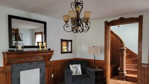 A living room with a fireplace, a chandelier, a sofa, and a staircase.