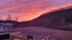 A bench and a small building in a rural setting with a sunset in the background.