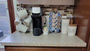 A kitchen with a coffee maker, mugs, and containers labeled 'Coffee' and 'Sugar'.