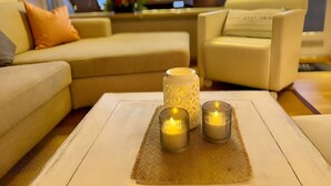 Una sala de estar con un sofá, sillones, una mesa de centro con velas y vista al mar.