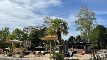 A beachside outdoor seating area with umbrellas, lounge chairs, and a stone wall.