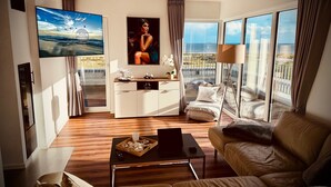 Una sala de estar moderna con un televisor grande, un sofá, una mesa de centro y un balcón con vistas.