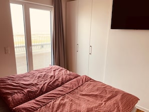 A room with a bed, a wardrobe, and a sliding door to a balcony.