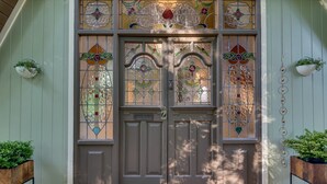 Una doppia porta con vetrate colorate e un piccolo portico con fioriere.