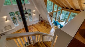 Un loft spazioso con soffitti alti, ampie finestre e una scala in legno.