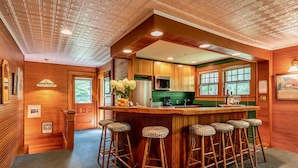 A bar area with wooden bar stools, a green countertop, and a kitchen with a microwave and refrigerator. - Ski season or yearly rental. Dogs loved! Walk to Equinox Pond & BBA. Fireplace (Manchester)