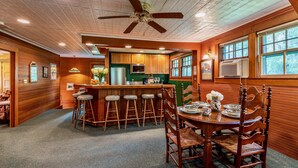 A kitchen with wooden cabinets, a bar area with stools, and a dining table with chairs. - Ski season or yearly rental. Dogs loved! Walk to Equinox Pond & BBA. Fireplace (Manchester)