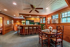 A kitchen with wooden cabinets, a bar area with stools, and a dining table with chairs.