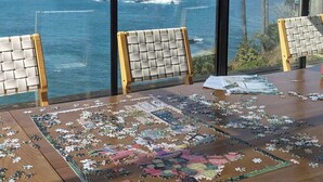 A puzzle table with a view of the ocean through large windows. - Seaflower Cove: Spacious 4bd Oceanfront Retreat (Gualala)