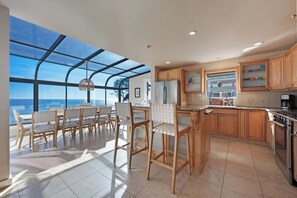 A modern kitchen with wooden cabinets, a stainless steel refrigerator, and a large window overlooking the ocean. - Seaflower Cove: Spacious 4bd Oceanfront Retreat (Gualala)