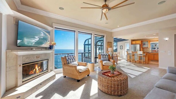 A spacious living room with a fireplace, large windows, and a view of the ocean. - Seaflower Cove: Spacious 4bd Oceanfront Retreat (Gualala)
