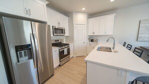 A modern kitchen with white cabinets, stainless steel appliances, and a central island with a sink.