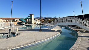 A swimming pool area with a curved design, a white bridge, and a water slide.