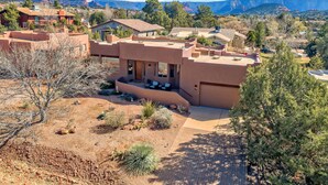 A modern house with a flat roof, surrounded by a desert landscape with mountains in the background. - Luxury Sedona Retreat • Hot Tub & Fire Pit (Sedona)