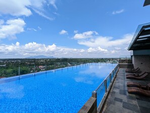 Une piscine à débordement située sur le toit, offrant une vue dégagée sur le paysage urbain et les montagnes au loin.