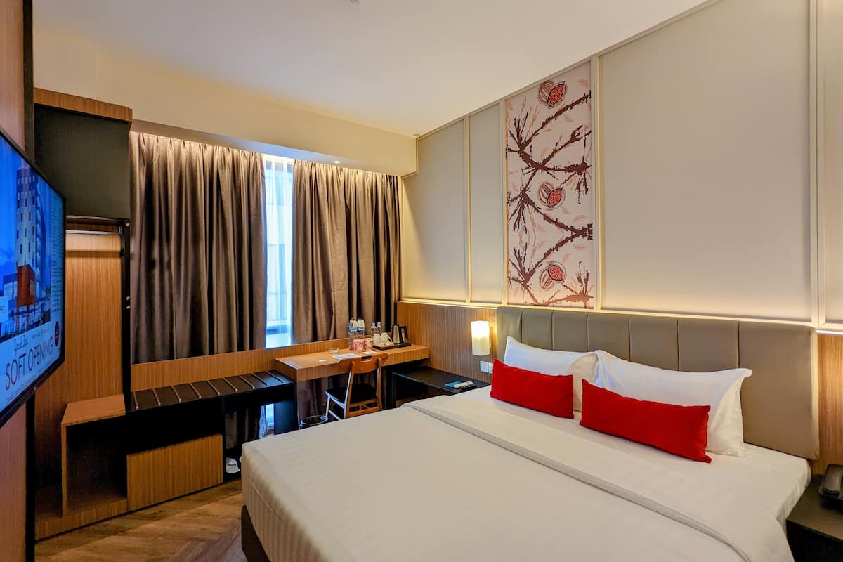 Une chambre d’hôtel avec un lit, un bureau, une chaise, une télévision et une fenêtre avec des rideaux.