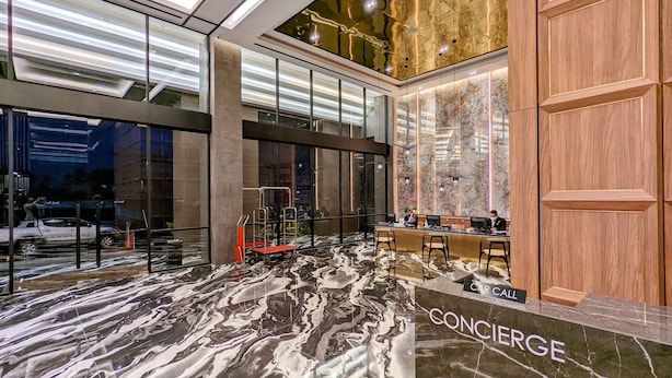 En modern entréhall med ett marmorgolv, en receptionsdisk och en biluthyrningstjänst.