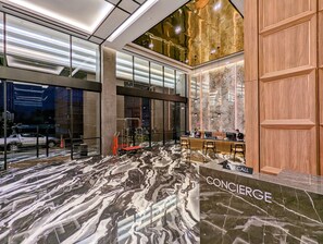 A modern lobby with a marble floor, a concierge desk, and a car rental service.
