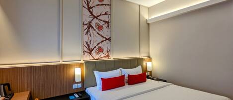 Una habitación de hotel con cama, mesita de noche, lámpara y un panel decorativo en la pared.