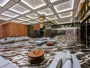 Un hall d’entrée spacieux avec un plafond haut, un mobilier contemporain et un sol en marbre.