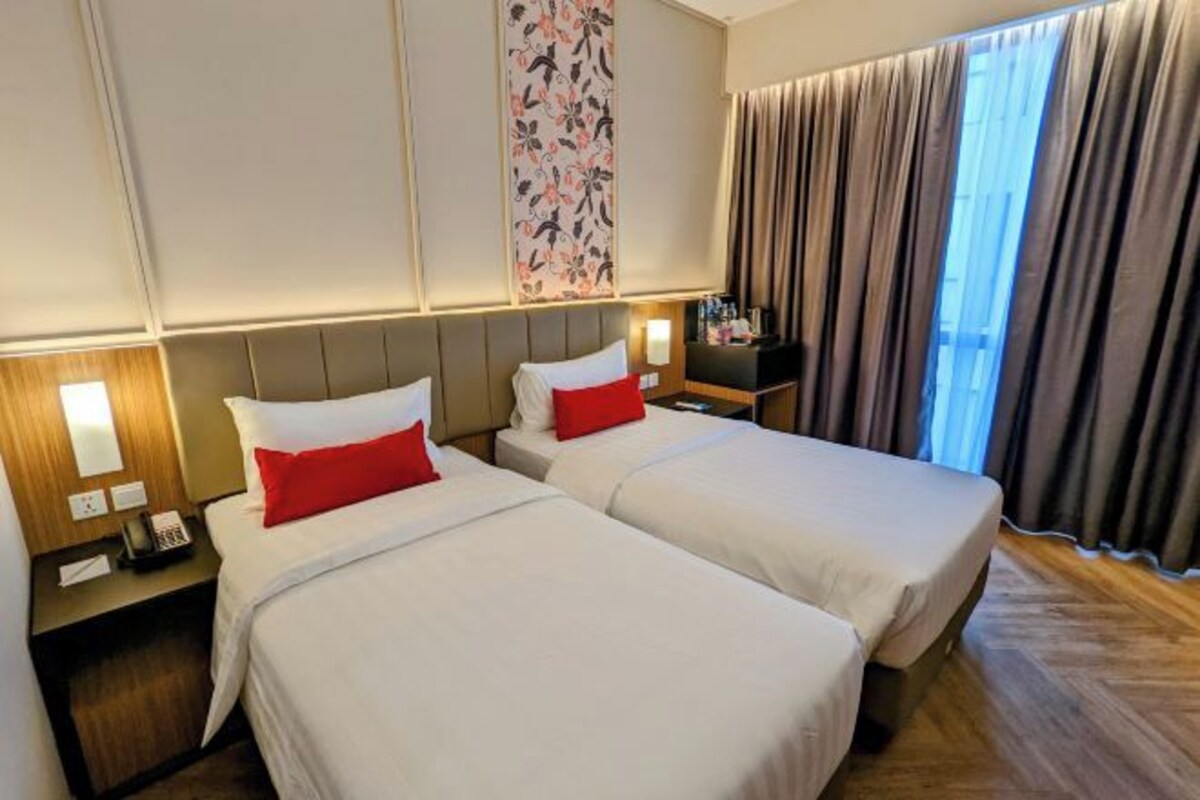 A hotel room with two beds, a nightstand with a phone, a wall-mounted TV, and a large window with curtains.