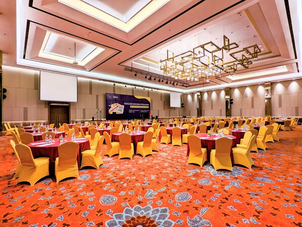 A large conference room with round tables, yellow chairs, and a patterned carpet.
