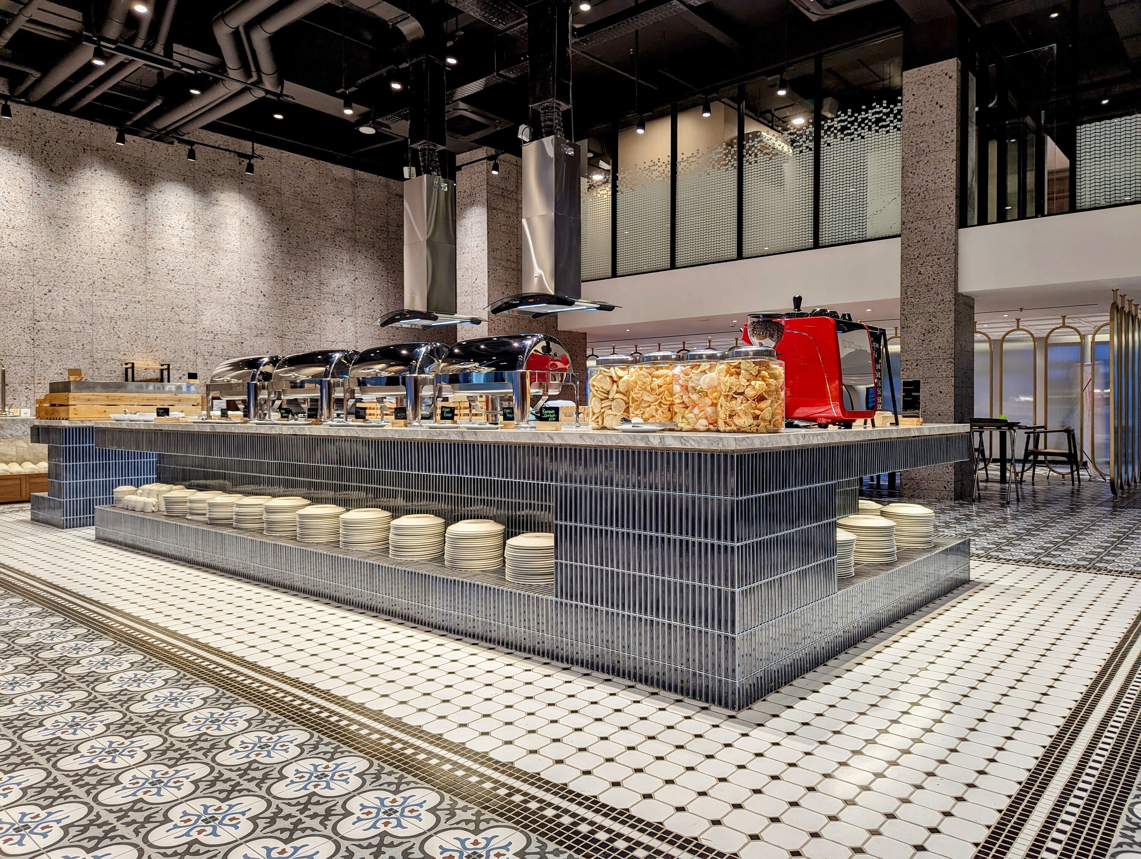Disposição moderna de buffet com ilha central, bandejas de servir e diversos recipientes com alimentos.