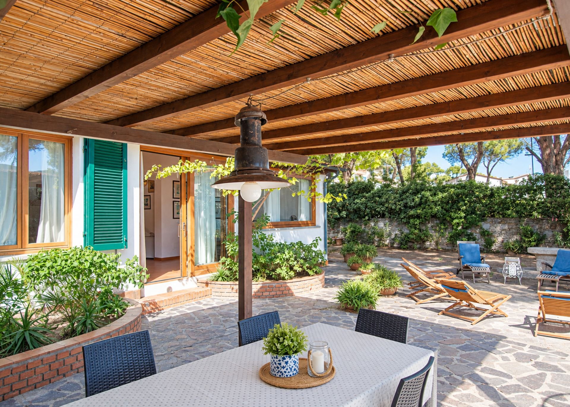 An outdoor patio with a table, chairs, and a hanging light fixture.