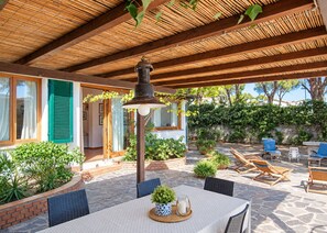 Une terrasse extérieure avec une table, des chaises et un luminaire suspendu.