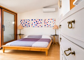 Een slaapkamer met een houten bed, een witte dressoir en een wandairconditioner.