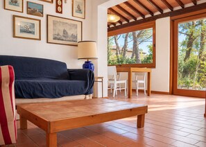 Een woonkamer met een bank, een houten salontafel, een lamp en een eethoek met stoelen.