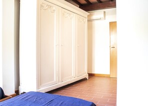 Een kamer met een grote witte kast, een houten deur en een betegelde vloer.