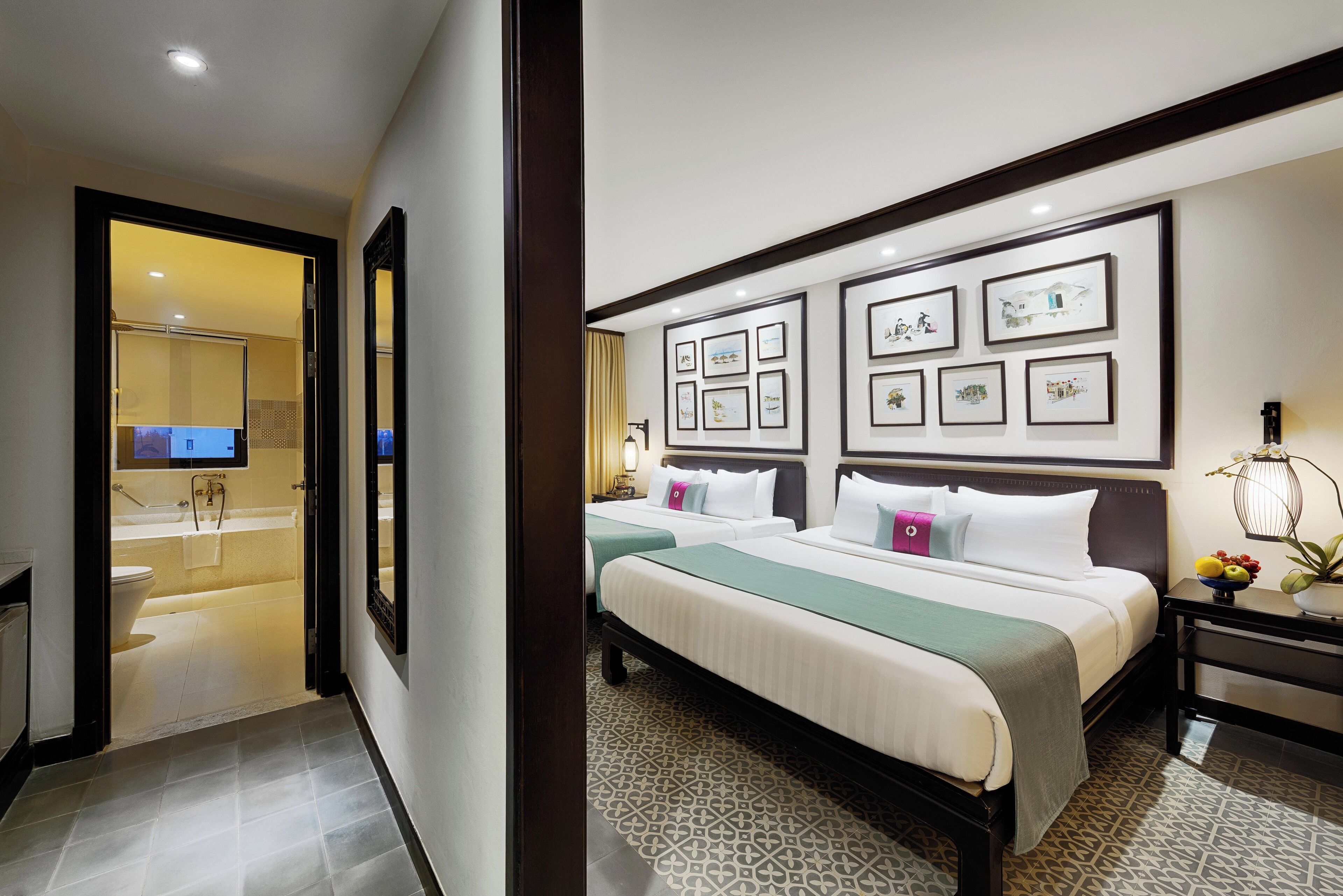 A hotel room with a bed, bedside tables, a wall-mounted TV, and framed artwork.