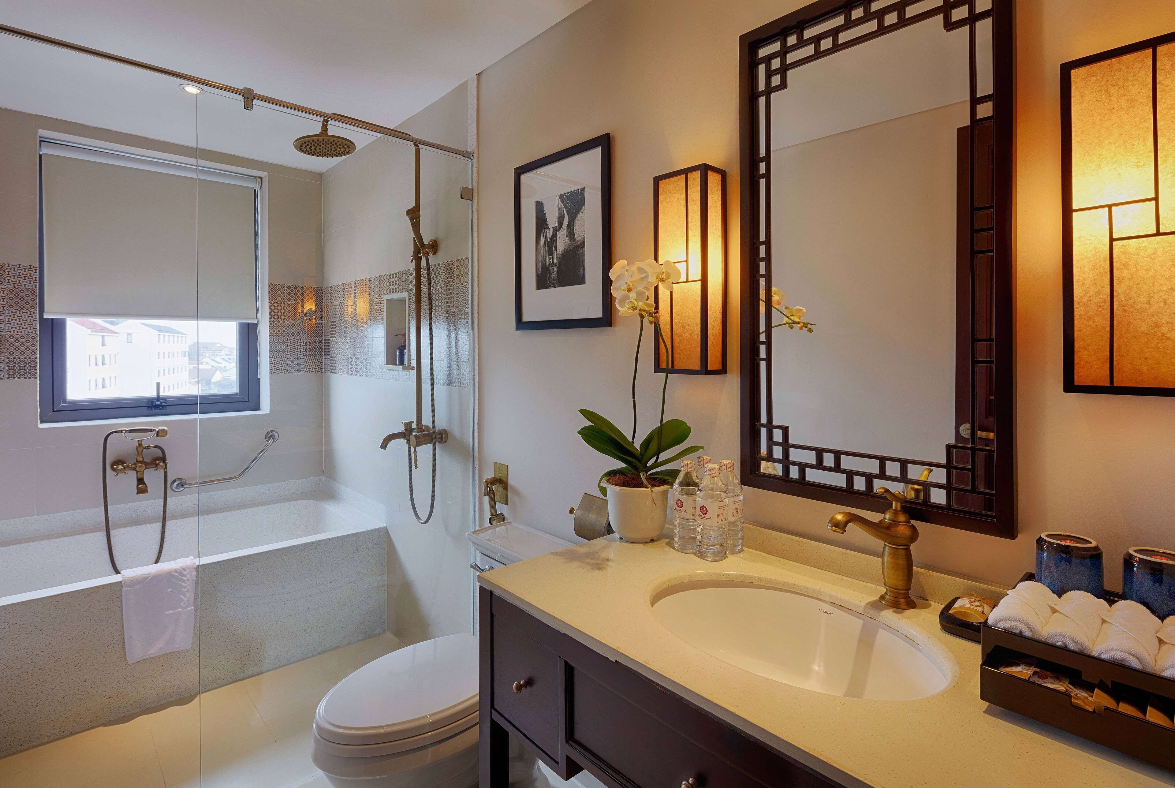 A modern bathroom with a glass-enclosed shower, a large mirror, and a vanity with a sink and towel rack.