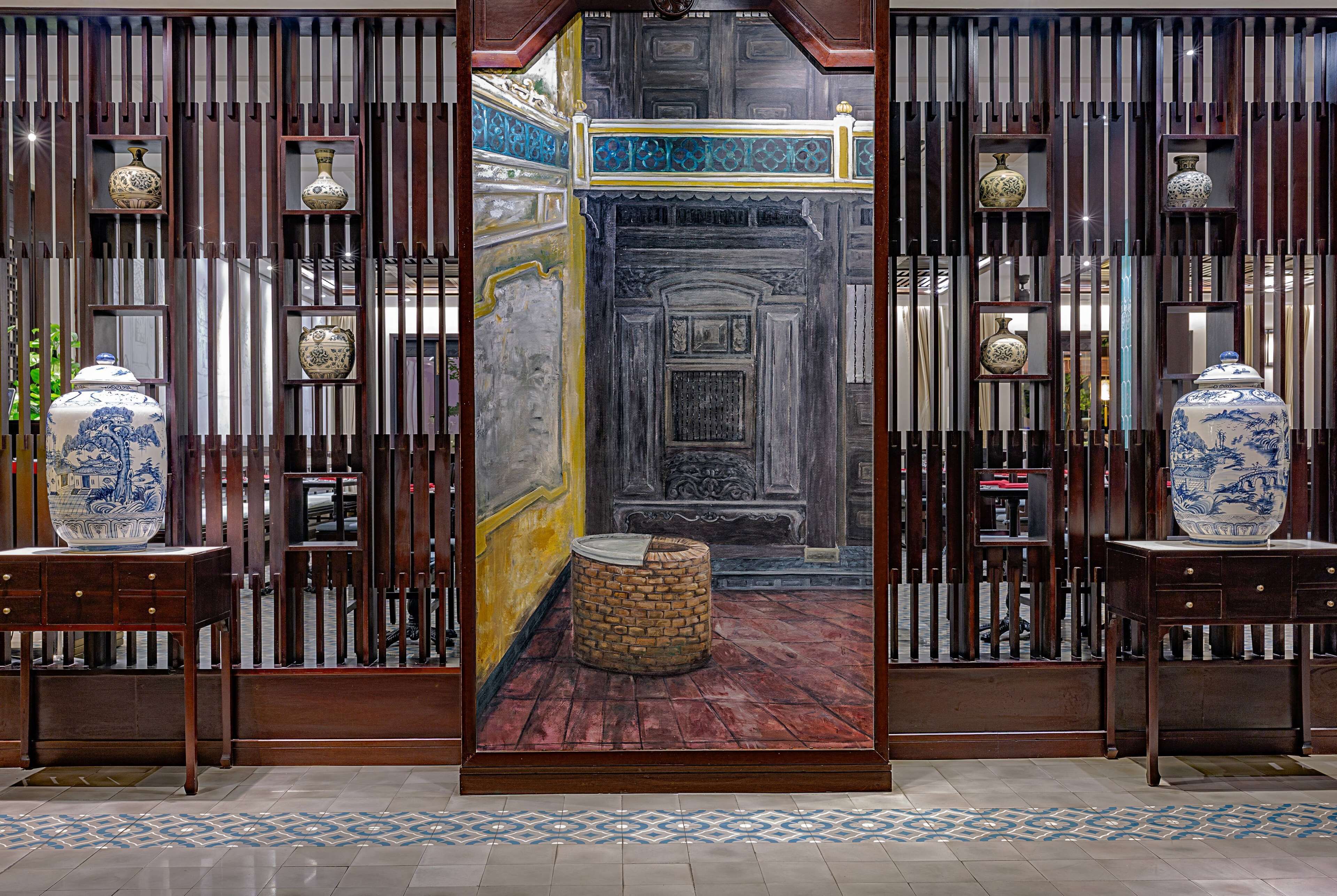 A traditional room with a wooden screen door, a patterned floor, and two vases on side tables.